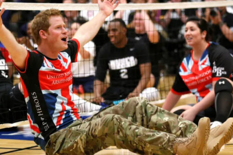 Prince Harry in a gym raising his arms cheering at the Invictus Games