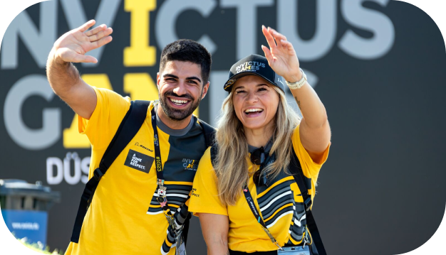 two volunteers waving at the Invictus Games
